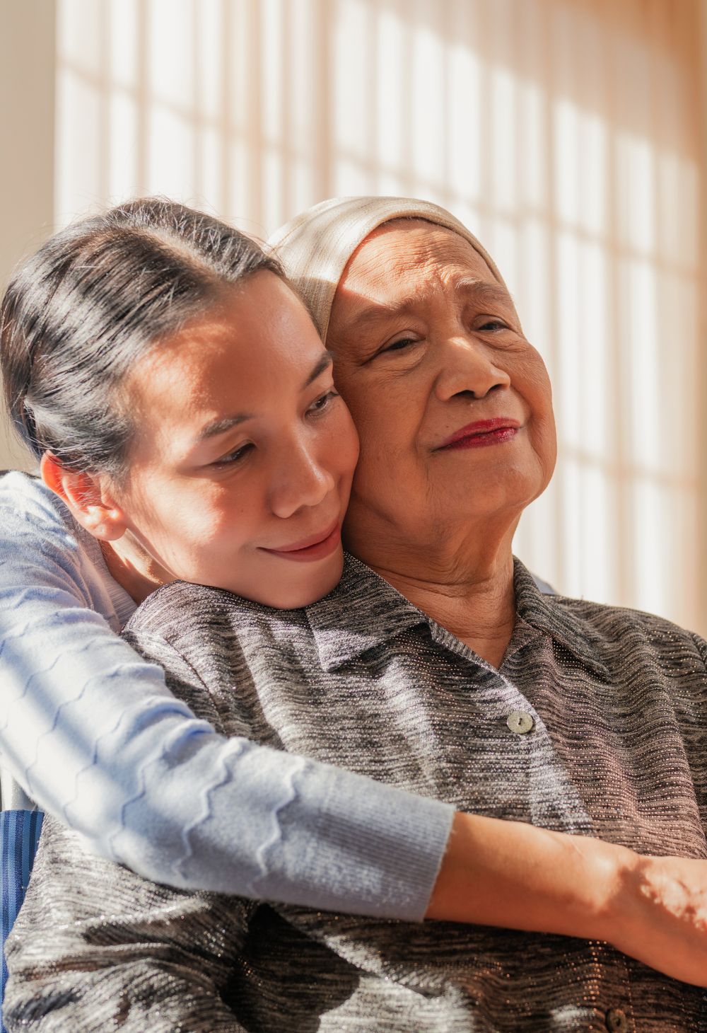 A caregiver showing compassion to a senior woman by hugging her from behind.