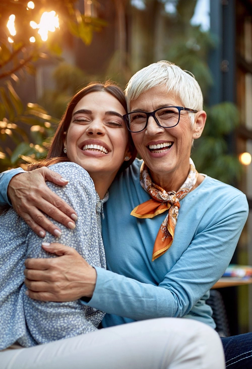 A young woman warmly hugging a smiling senior woman outdoors, showing companionship, emotional support, and joyful connection.