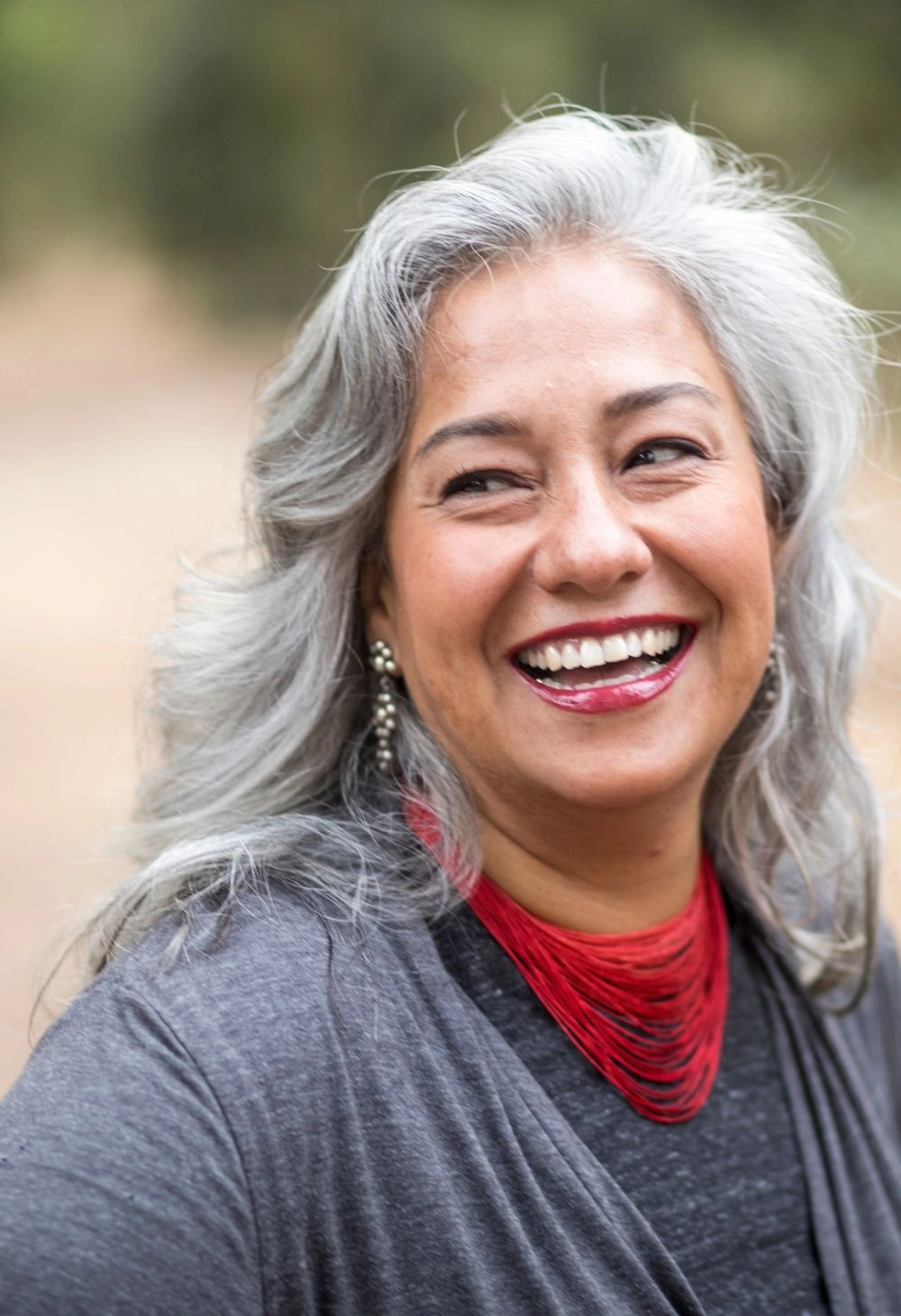Senior woman smiling outdoors A happy senior woman with long gray hair smiling while standing outside.