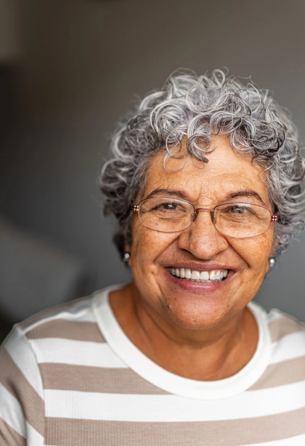 Smiling senior woman in stripped white and tan shirt