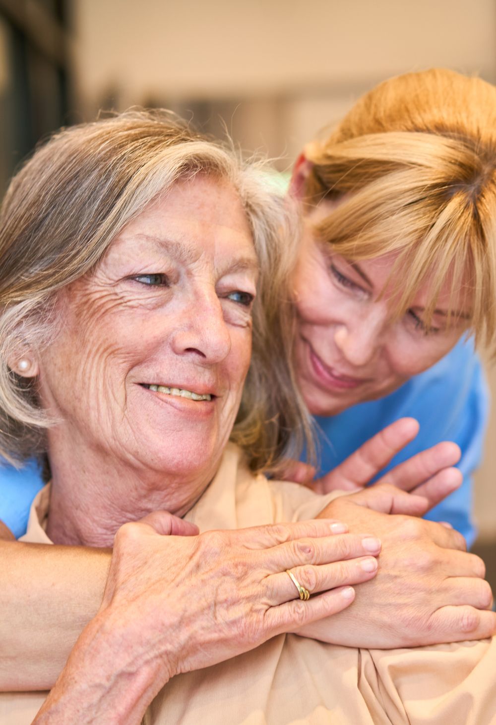 Caregiver in blue scrubs speaking with an elderly woman, providing emotional support during an in-home care visit
