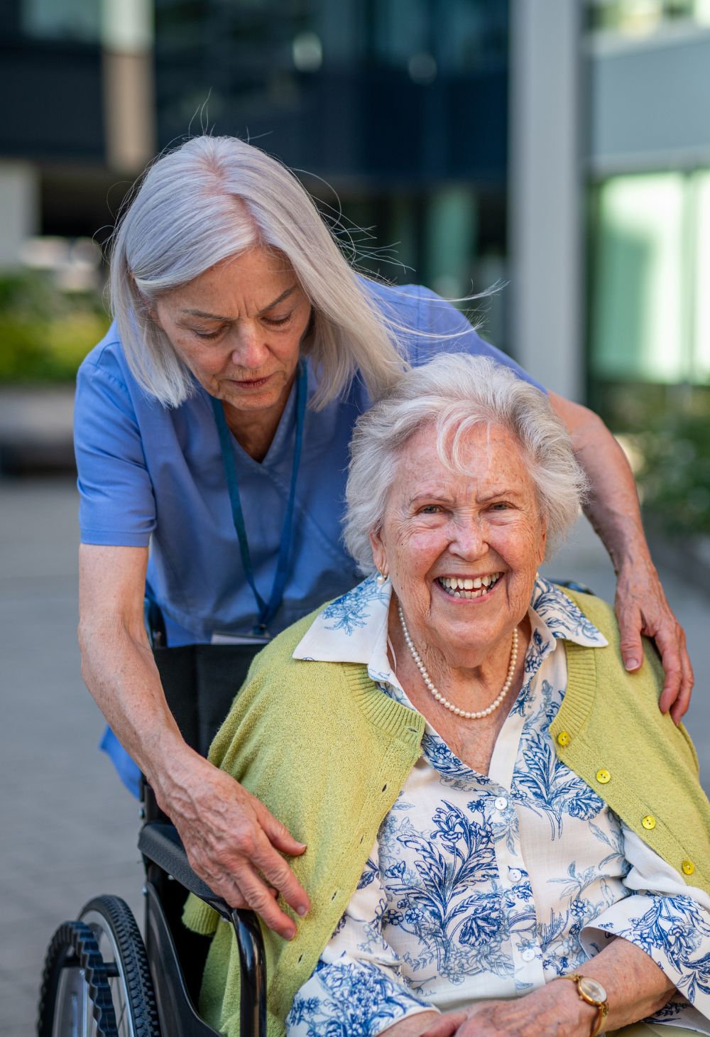 Caregiver Assisting a Smiling Senior in a Wheelchair in San Marcos A caregiver gently assists a joyful senior woman sitting in a wheelchair during an outdoor outing.