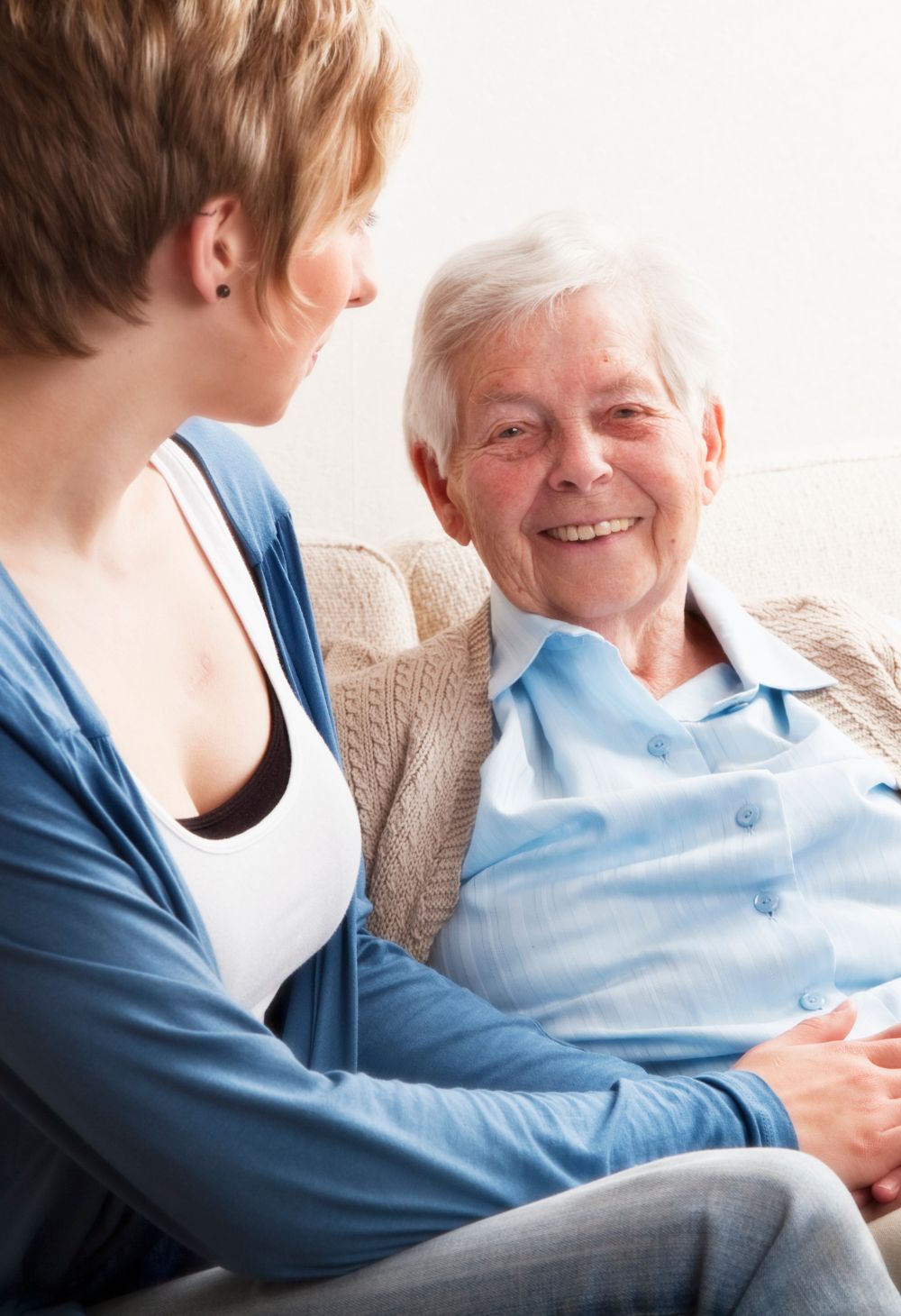 Caregiver Providing Companionship to Senior at Home in San Marcos A smiling senior woman sits comfortably on a couch with a caregiver offering friendly companionship and support.